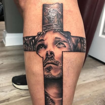 Black and grey realism tattoo of Jesus with crown of thorns formed inside a cross on the leg