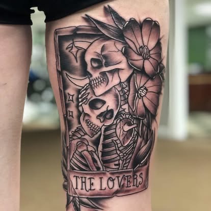 Black and grey The Lovers tarot card with skeletons and flowers tattoo on the thigh