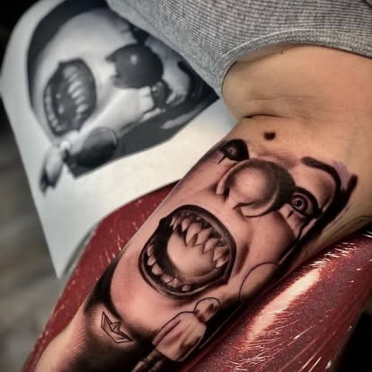 Black and grey realism screaming clown face tattoo on the arm from a reference book