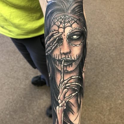 Black and grey Day of the Dead sugar skull girl with a spiderweb and skeleton hand tattoo on the forearm