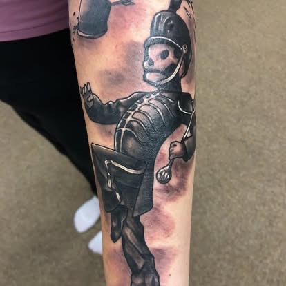 Black and grey neo-traditional armored tin man knight with a skull face tattoo on the forearm