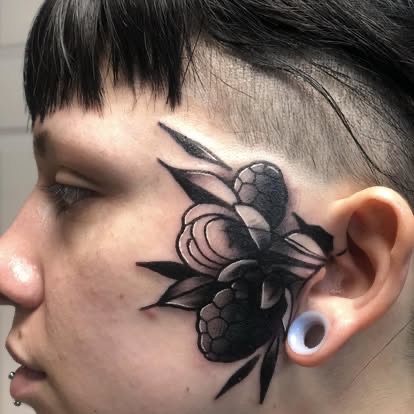 Blackwork bee and flower tattoo on the side of the head