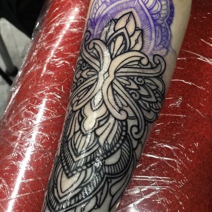 Blackwork ornate mandala cross tattoo on the forearm