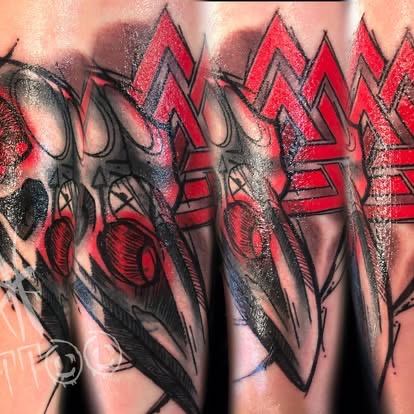 Red and black trash-polka style abstract skull tattoo on the forearm