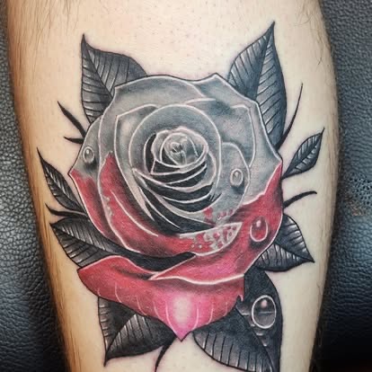 Neo-traditional black and red rose tattoo with water droplets on the leg