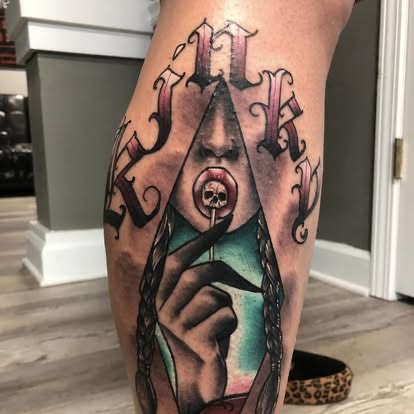 Neo-traditional color KINKY lettering with a hand holding a lollipop tattoo on the calf