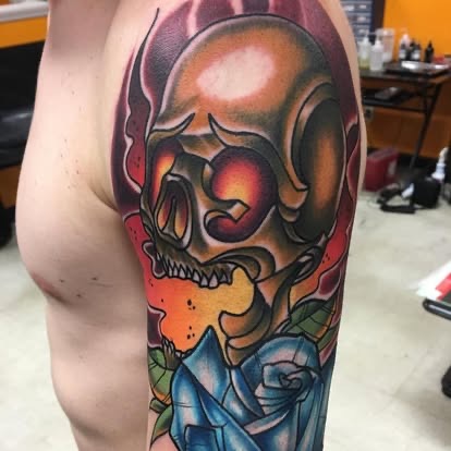 New-school color horned skull tattoo with a blue rose on the arm