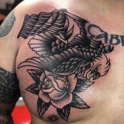 Black and grey traditional eagle with American flag and rose chest tattoo